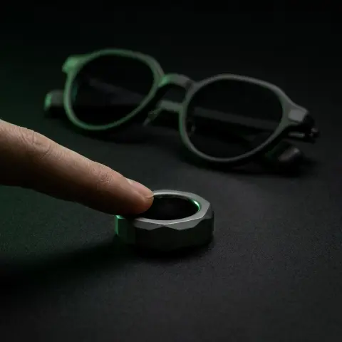 A fingertip on the ring, the glasses dark behind it