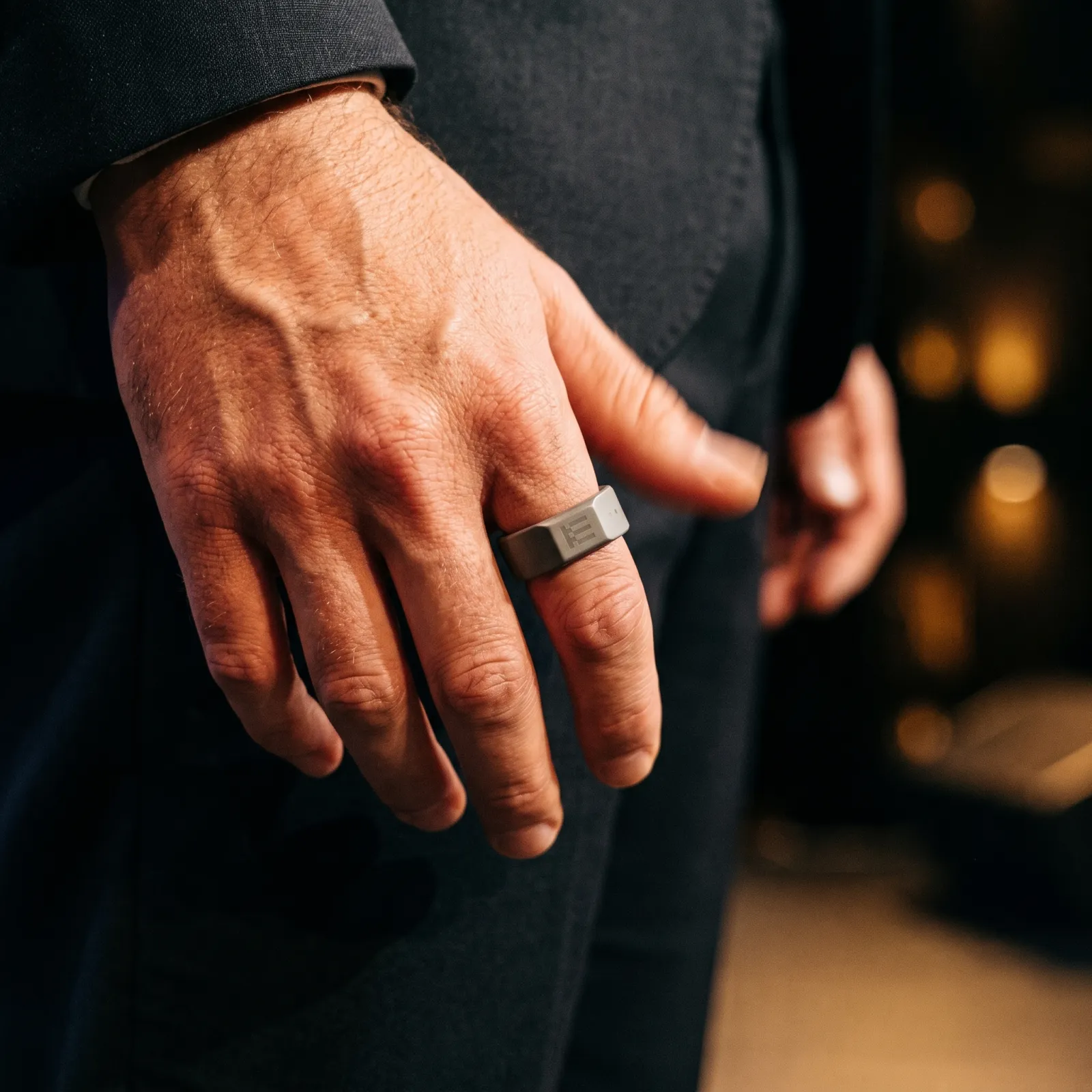 A thumb resting on the ceramic ring at a trouser seam